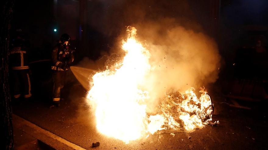 Los bomberos apagan los contenedores que los manifestantes han quemado en la Via Augusta de Barcelona este martes