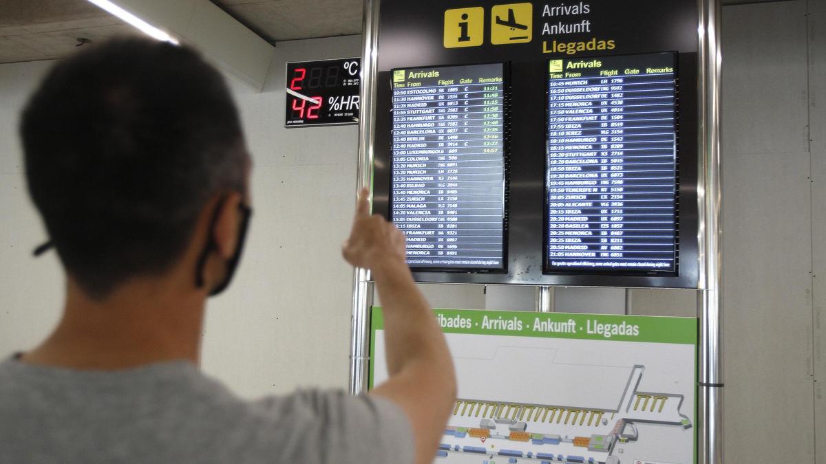 Archivo - Un pasajero señala la pantalla del aeropuerto de Palma.