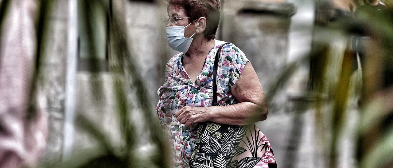 Una mujer pasea portando su mescarilla por una calle de Tenerife.