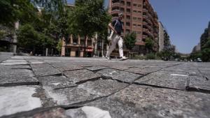 Un peatón pasa por un paso de cebra con el adoquinado maltrecho en la calle Pi i Margall, en Barcelona.