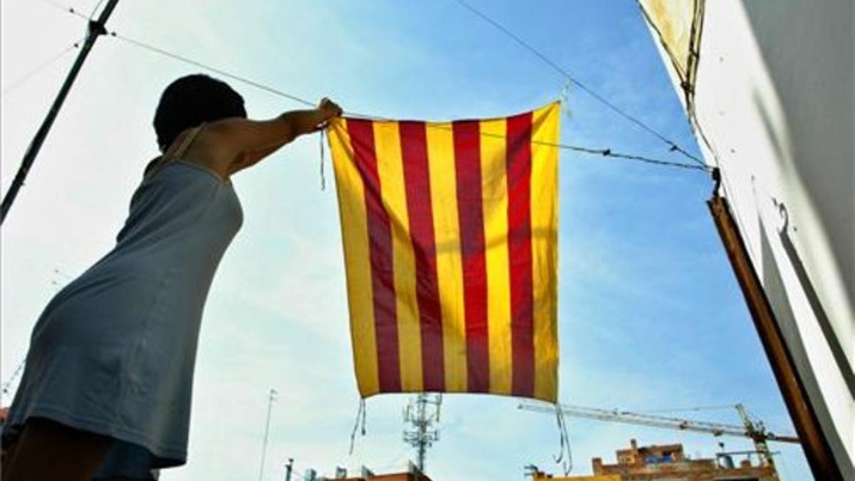 Una chica cuelga la bandera catalana en la terraza de su casa para la Diada del 2004.