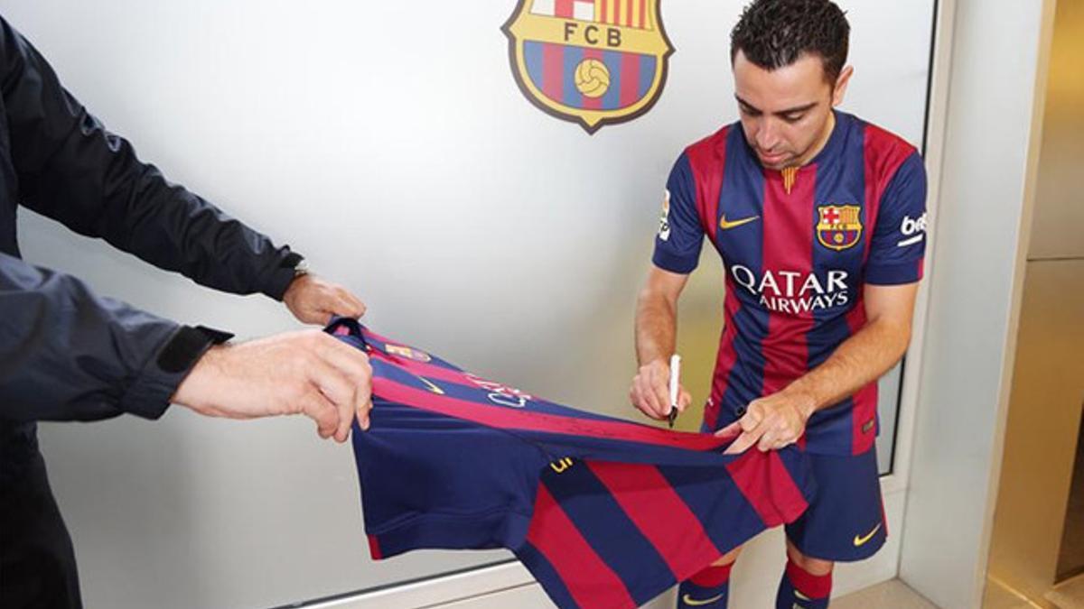 Xavi firmando la camiseta con la que el FC Barelona colaborará para recuperar la figura de Patrick O'Connell