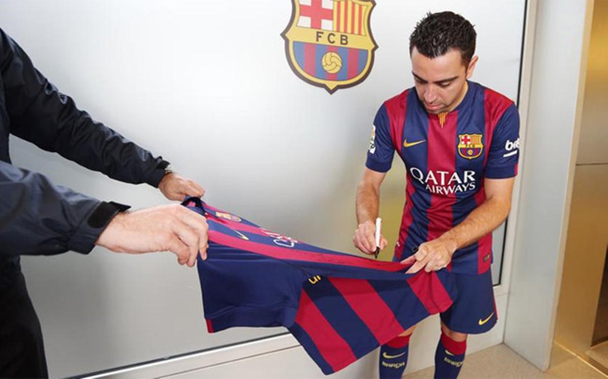 Xavi firmando la camiseta con la que el FC Barelona colaborará para recuperar la figura de Patrick O'Connell