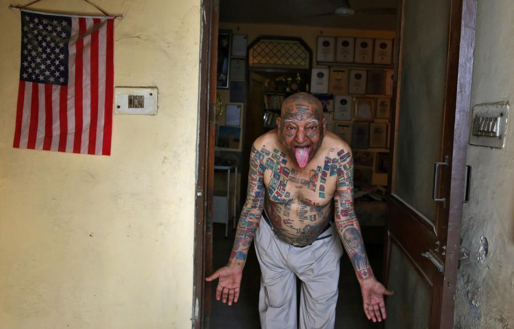 Guiness Rishi, el hombre de 74 años residente en Nueva Delhi que poseé el record a la persona con más banderas tatuadas en su cuerpo, posa frente a su apartamento.