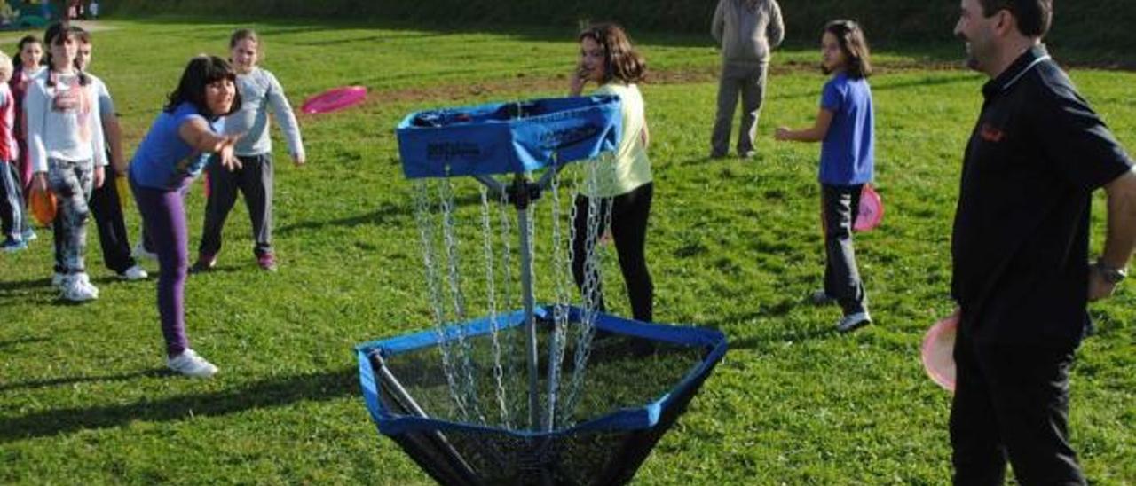 Alumnos de sexto de Primaria juegan al &quot;disc golf&quot; bajo la supervisión de Carlos Río, a la derecha.