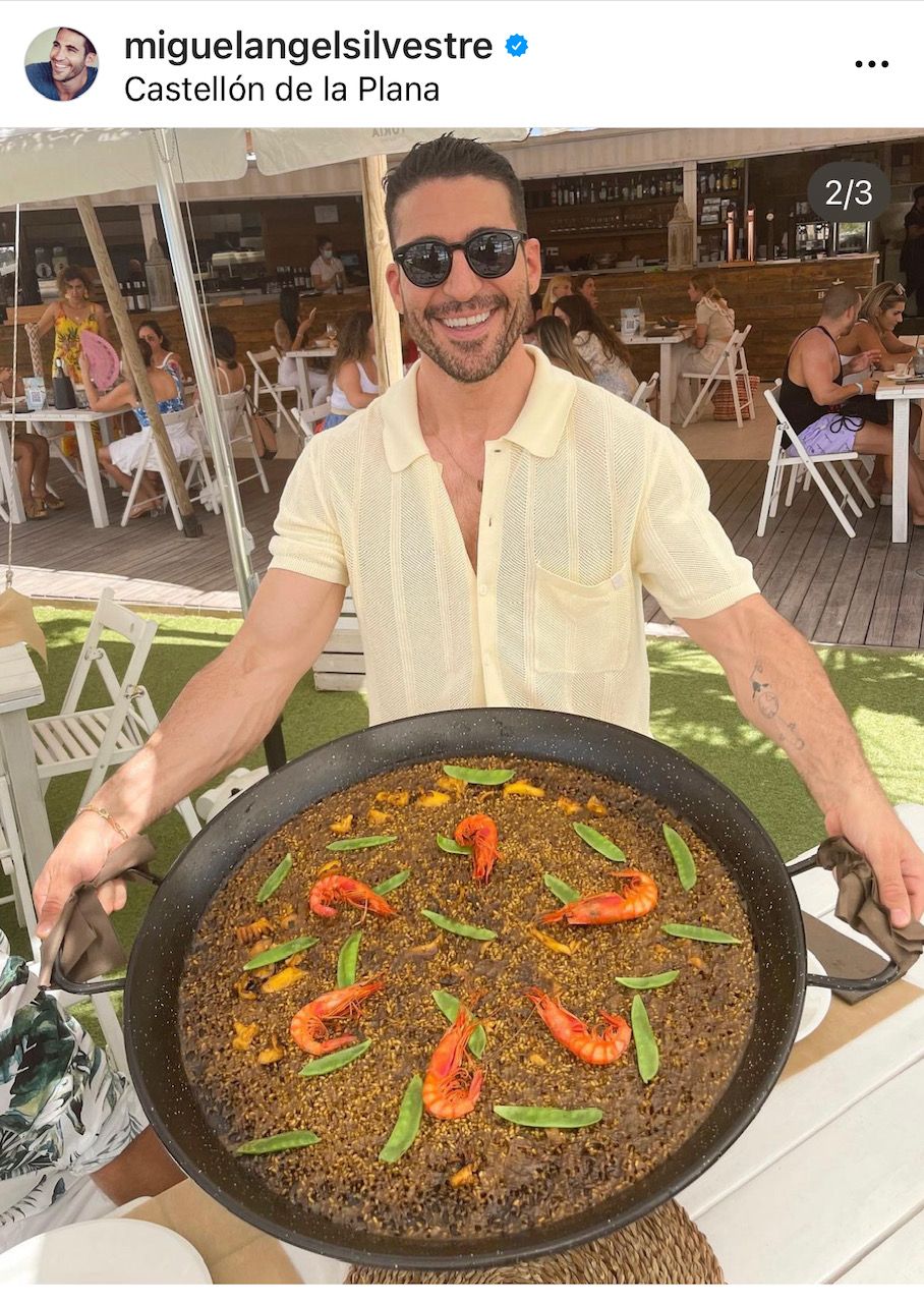 Silvestre, muy sonriente, sostiene una gran paella entre sus manos.