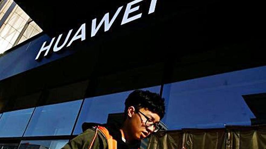 Un usuario de móvil pasa junto a una sede de la compañía Huawei.