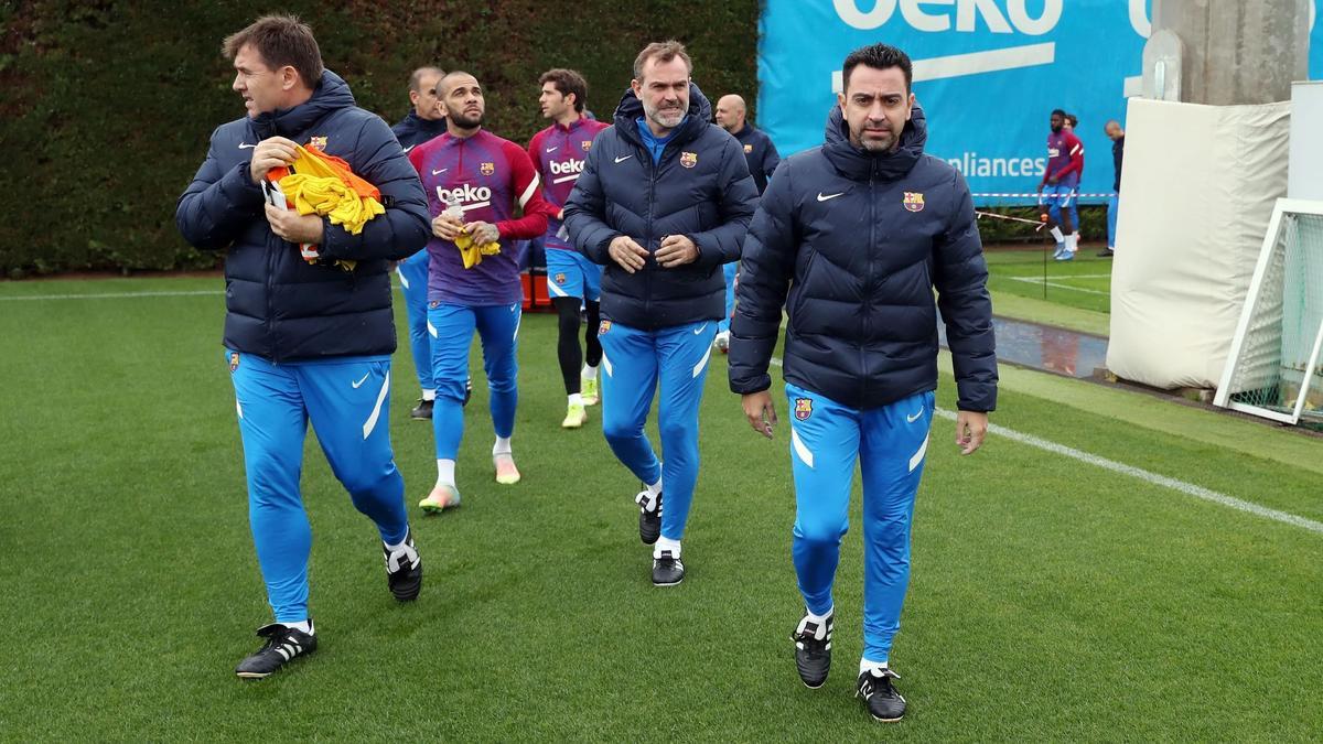 Xavi y su cuerpo técnico entran en el campo de entrenamiento.