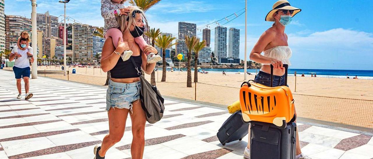 Dos turistas británicas caminaban, ayer, con sus maletas, por el paseo de la playa de Levante de Benidorm. | DAVID REVENGA