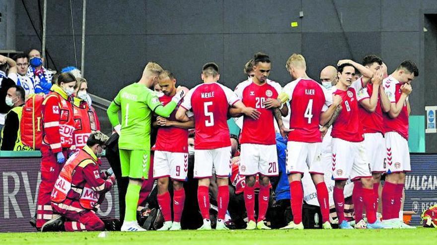 Los futbolistas daneses protegen la intimidad de su compañero durante la atención médica, el sábado en Copenhague. |