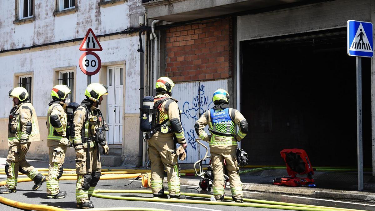 Efectivos de los Bomberos durante la extinción del incendio de un coche en un garaje en la rúa das Santas Mariñas