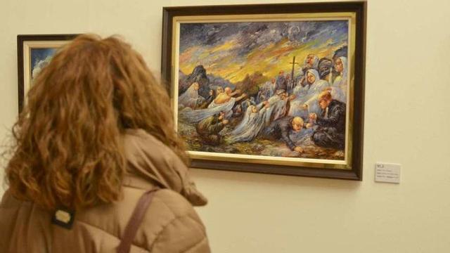 Una visitante observa uno de los cuadros de la muestra 'Colectiva de Navidad'.