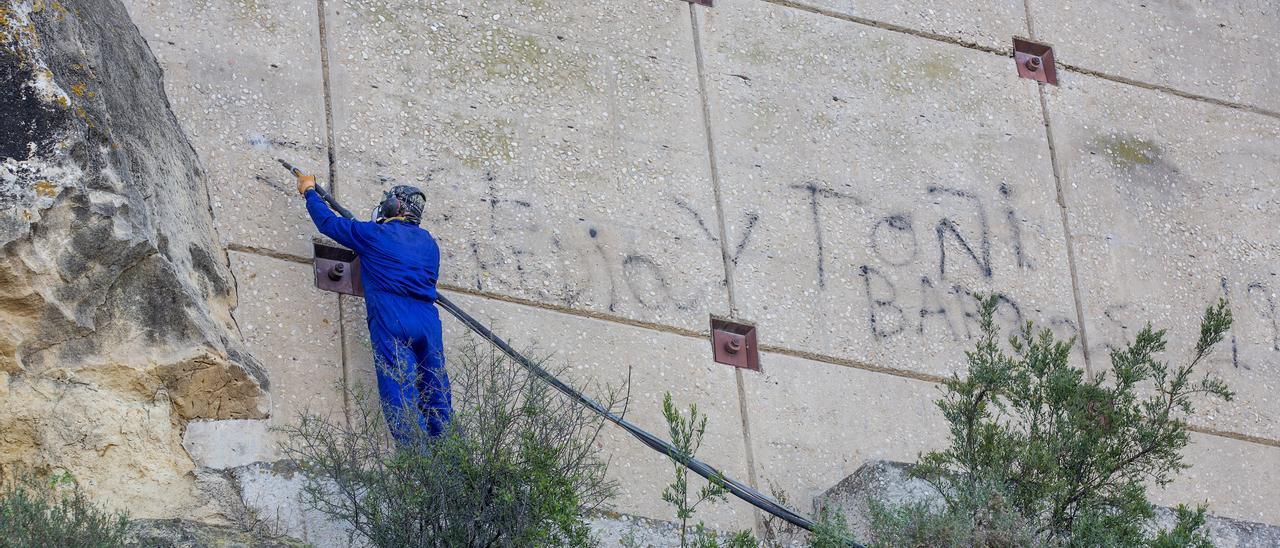 Un operario pinta una pintada esta mañana en el Castillo de Santa Bárbara