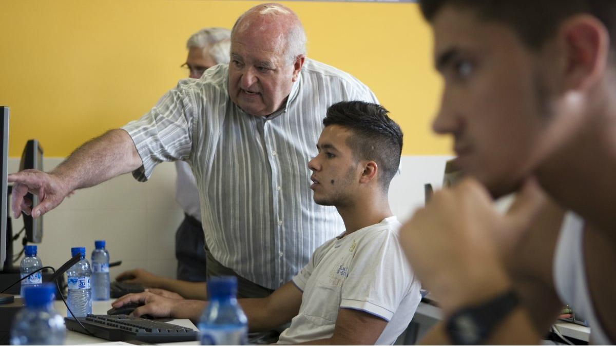 Una persona jubilada enseña de forma voluntaria informática a jóvenes, en La Roca del Vallès.