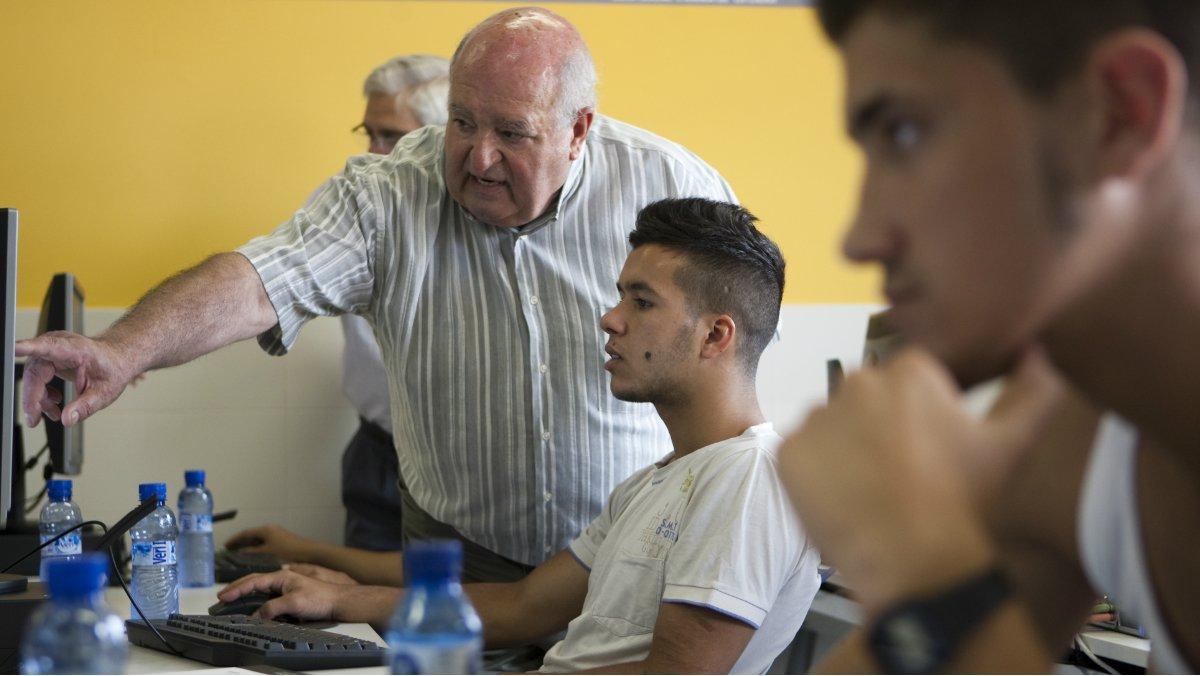 Una persona jubilada enseña de forma voluntaria informática a jóvenes, en La Roca del Vallès.
