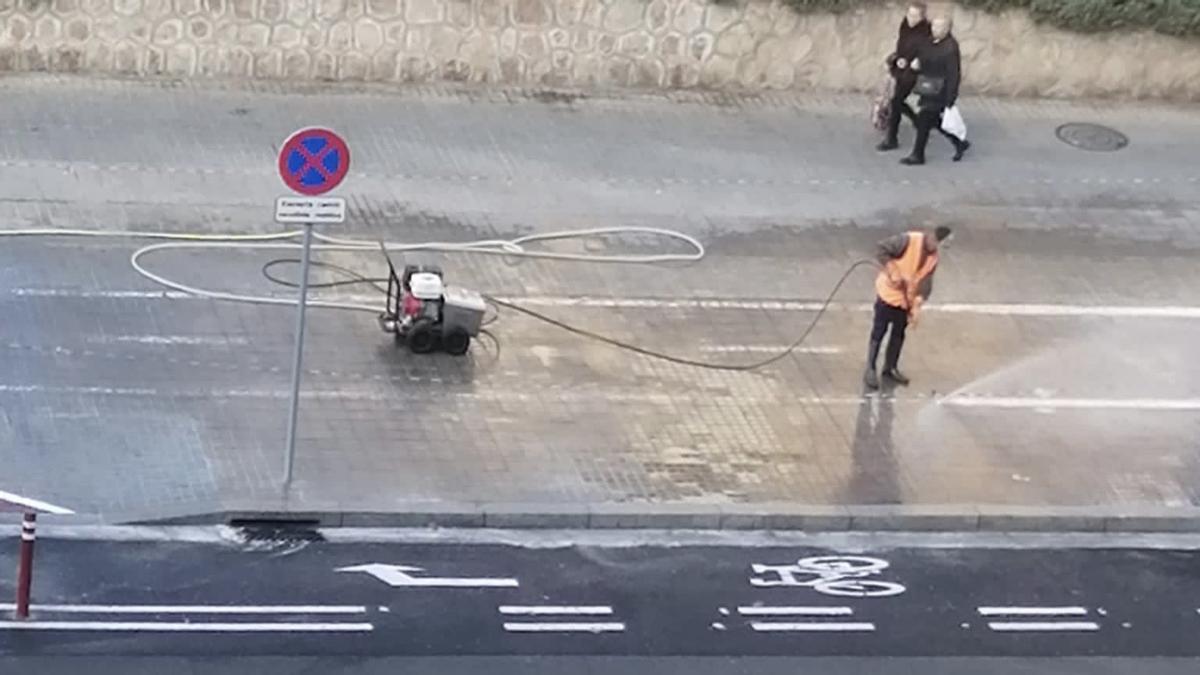 Un operario borra las señales de un carril bici con agua potable, en Barcelona.