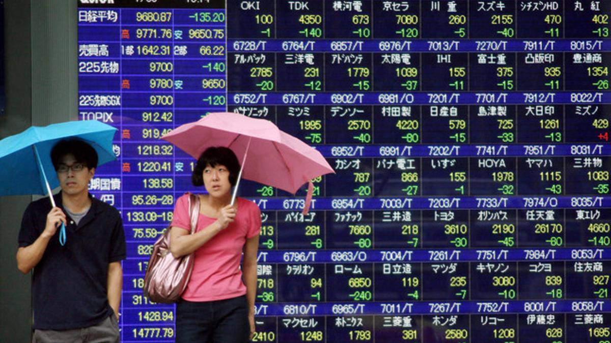 Una pareja de japoneses, frente a un panel electrónico de valores bursátiles en Tokio.