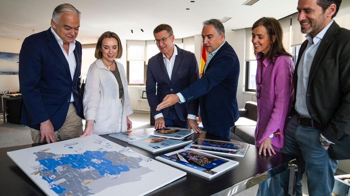 Feijóo, con su cúpula del PP, este lunes, observa un mapa de España en el que están en azul las autonomías donde se celebran elecciones este 28 de mayo.