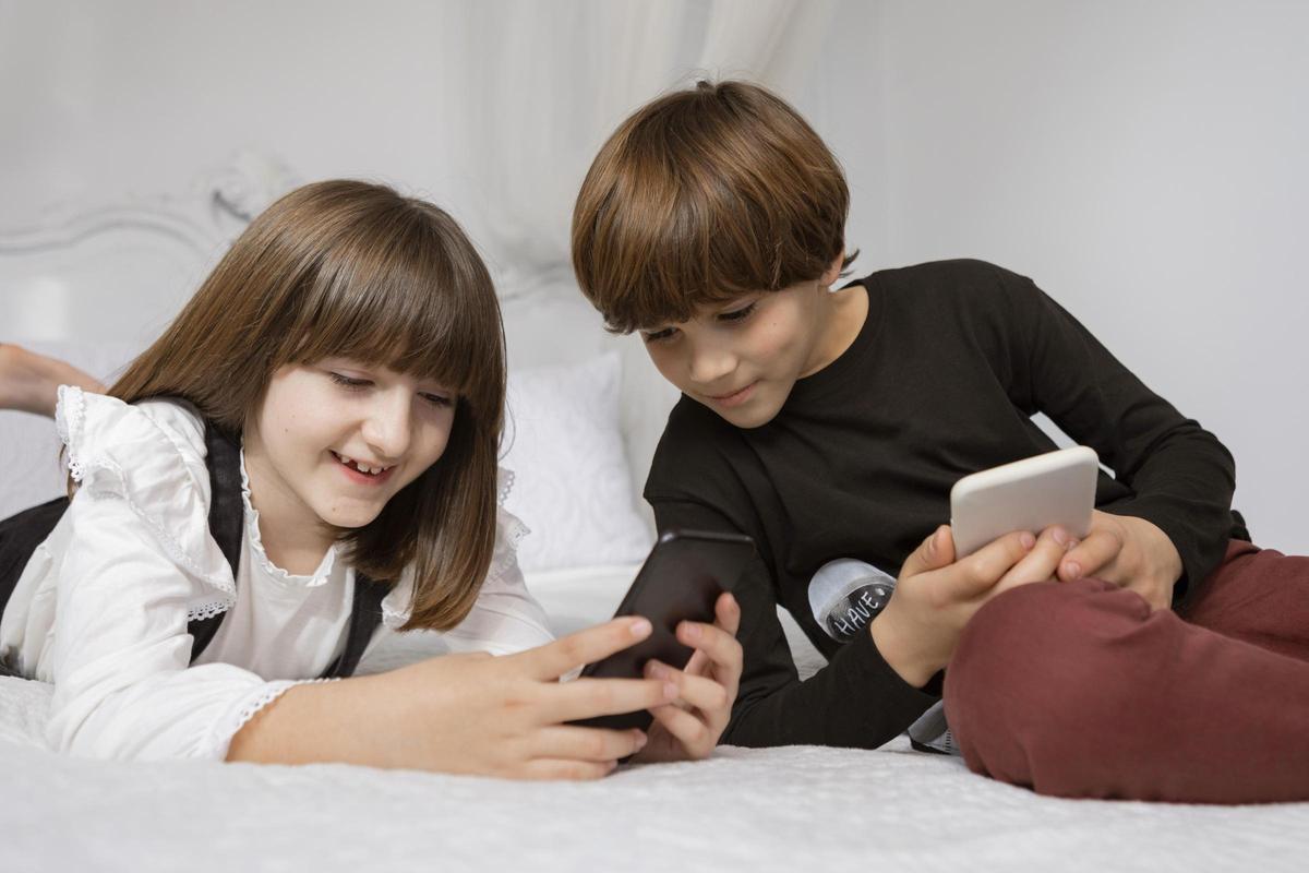 Un par de niños usando su teléfono móvil.