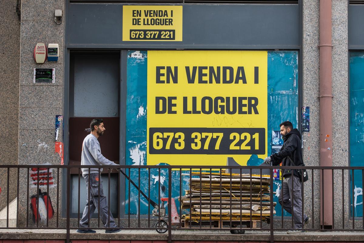 Dos personas pasan frente a un cartel de 'Se alquila' en Badalona.