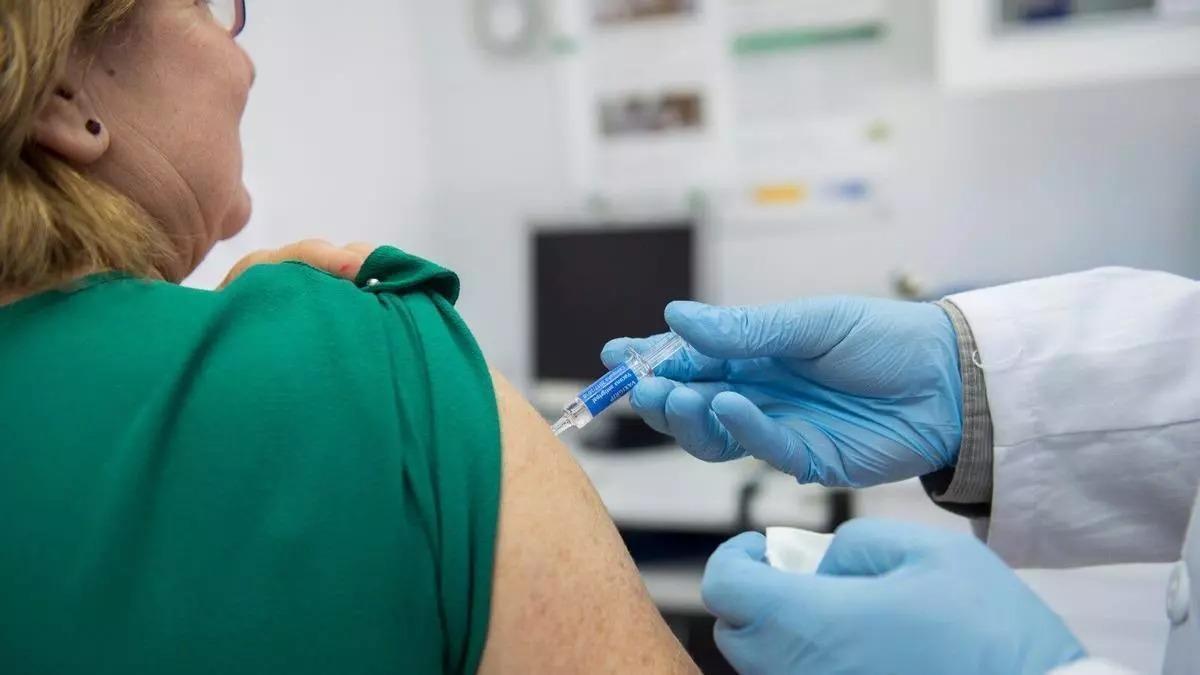 Un enfermero vacuna a una mujer de la gripe.