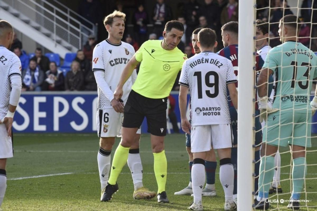 Ais Reig advierte a los jugadores del Ceuta y del Huesca antes de una jugada a balón parado.
