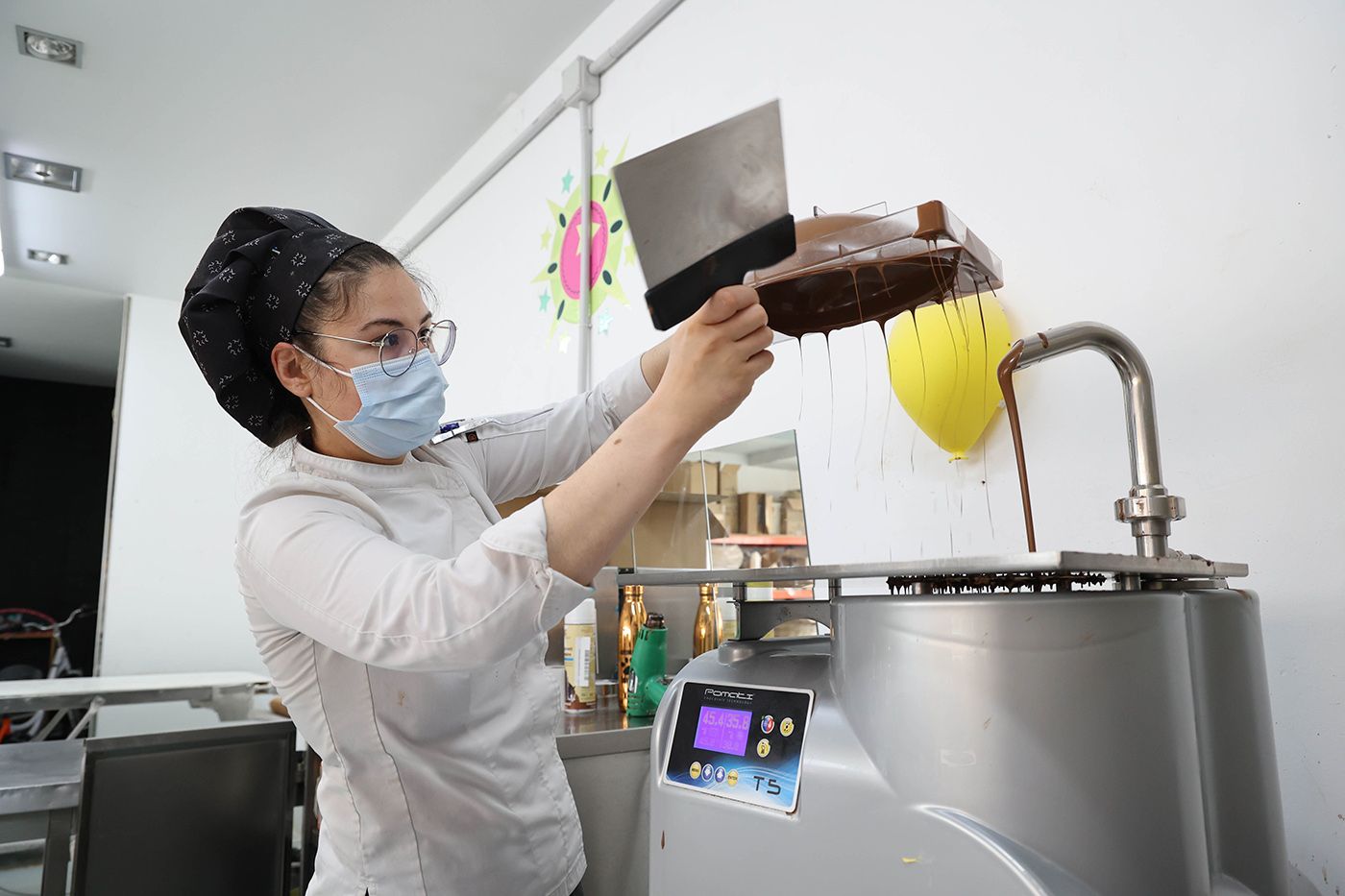 Una confitera, trabajando el chocolate para los  huevos de Pascua en El Trigal.