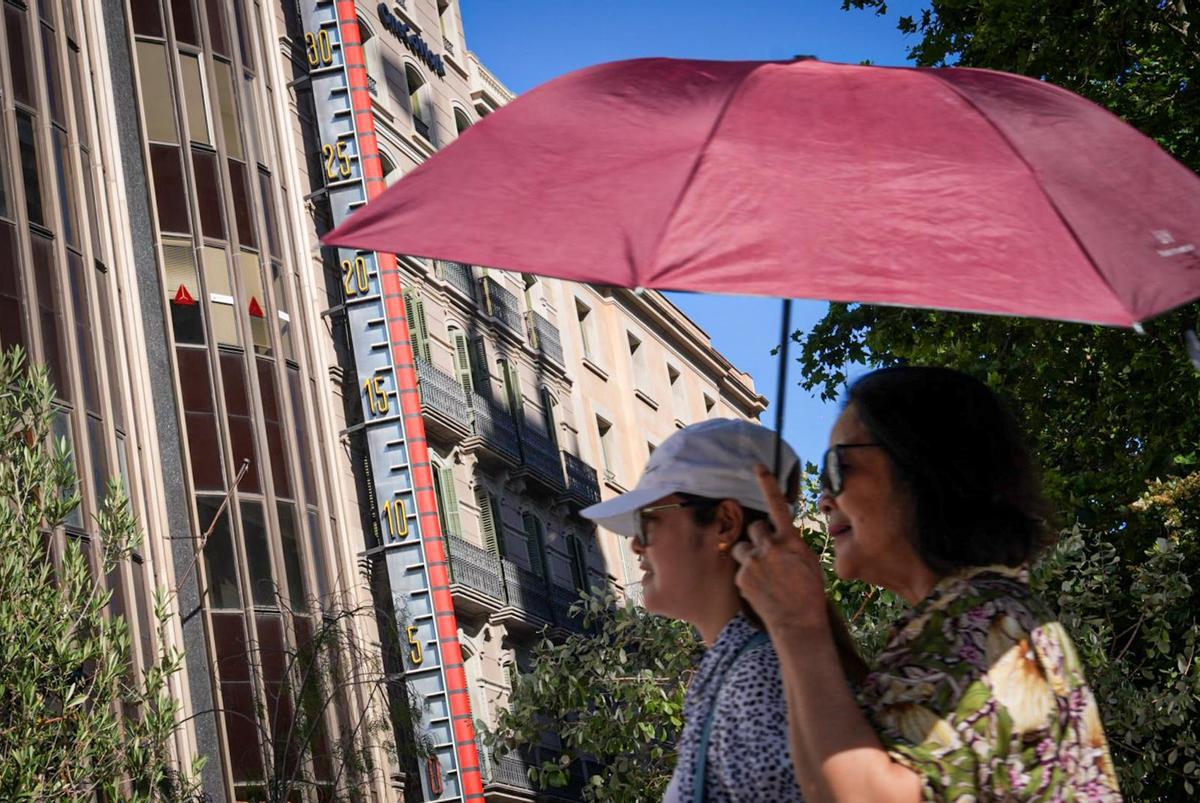 Unas mujeres se refugian del sol bajo un paraguas durante un viernes de altas temperaturas en Barcelona. Unas mujeres se refugian del sol bajo un paraguas durante un viernes de altas temperaturas en Barcelona.