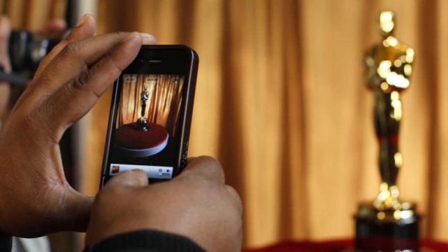 Un hombre fotografía un Oscar en el Teatro Kodak.