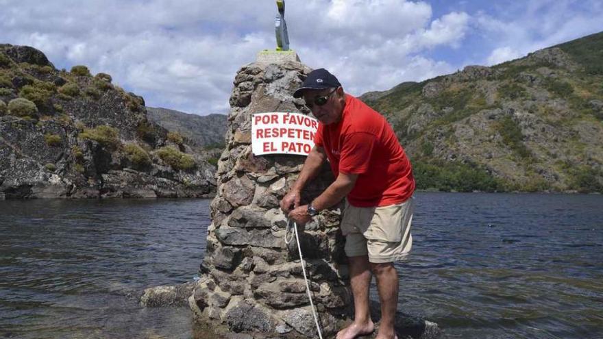 César Fernández coloca el cartel en el pilar del pato.