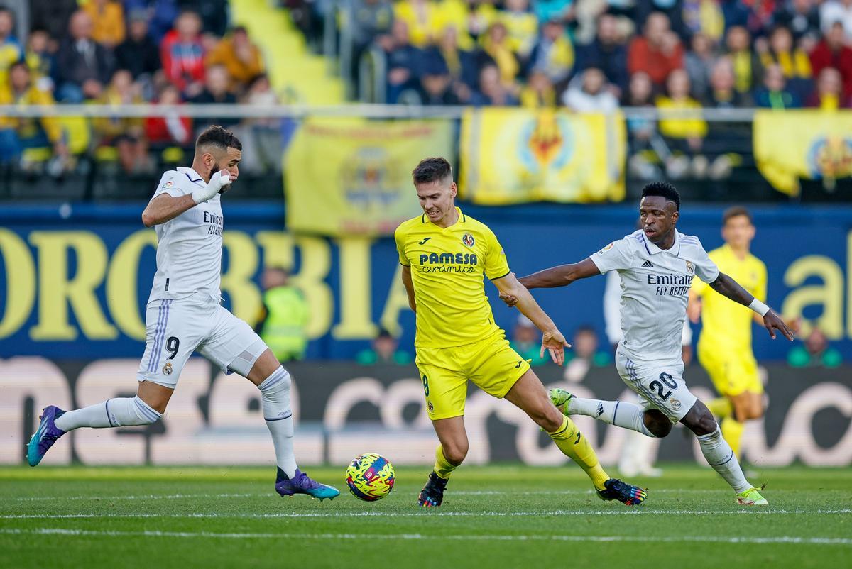 VILLARREAL, 07/01/2023.-El defensa del Villarreal Juan Foyth con el balón ante los jugadores del Real Madrid Karim Benzema (i) y Vinicius Jr durante el partido de la jornada 16 de LaLiga Santander que el Villarreal y el Real Madrid disputan este sábado en el estadio de La Cerámica en Villarreal.- EFE / Biel Alino