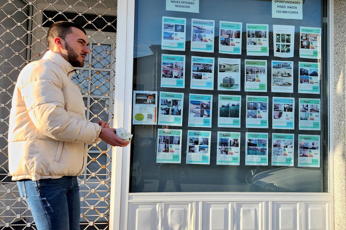 Foto de archivo de un joven caminando ante el escaparate de una inmobiliaria.