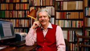 Lluís Permanyer, en su casa, junto a la mesa de su despacho y su gigante biblioteca personal.