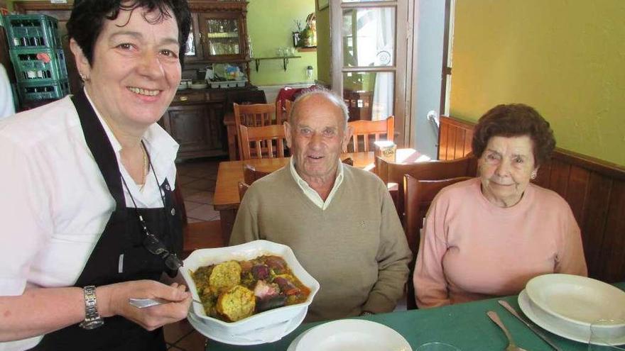 Josefina de la Fuente, ayer, sirviendo pote a José Gutiérrez y Luz Díaz en la sidrería La Casona.