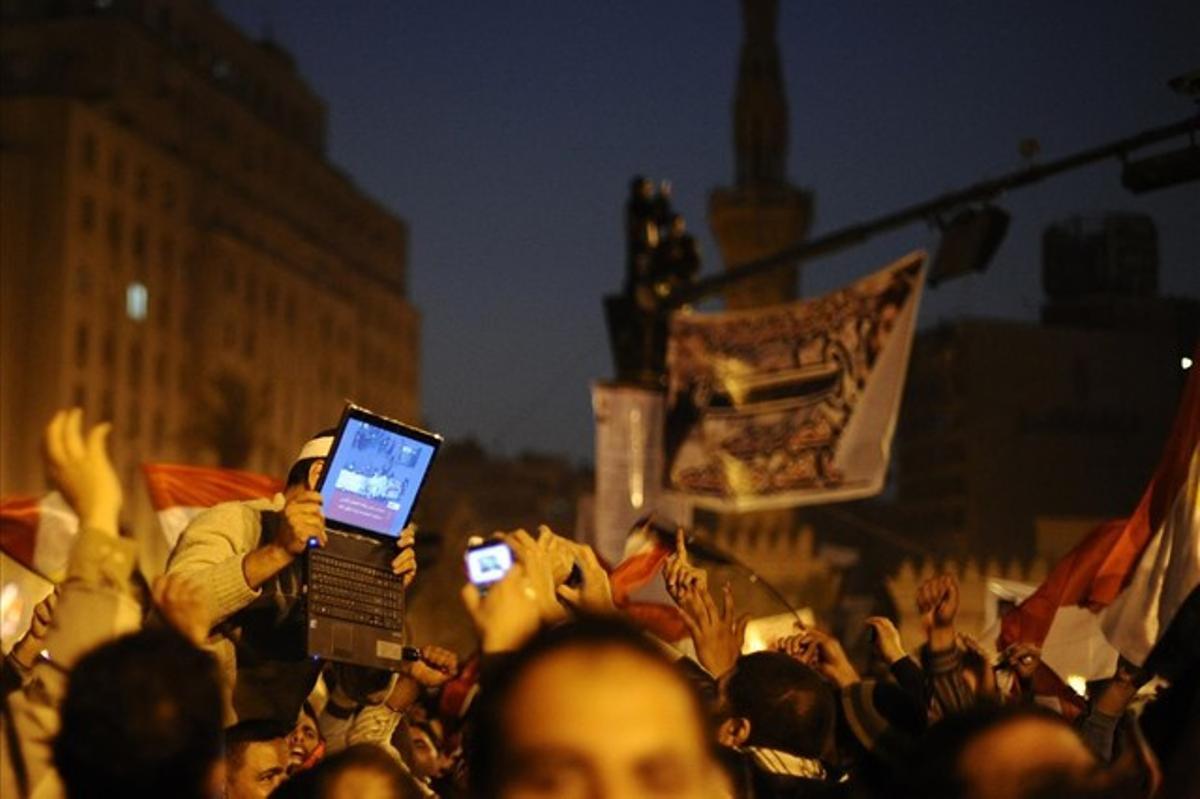 An opposition supporter holds up a laptop showing images of celebrations in Cairo’s Tahrir Square, after Egypt’s President Hosni Mubarak resigned in this February 11, 2011 file photo.