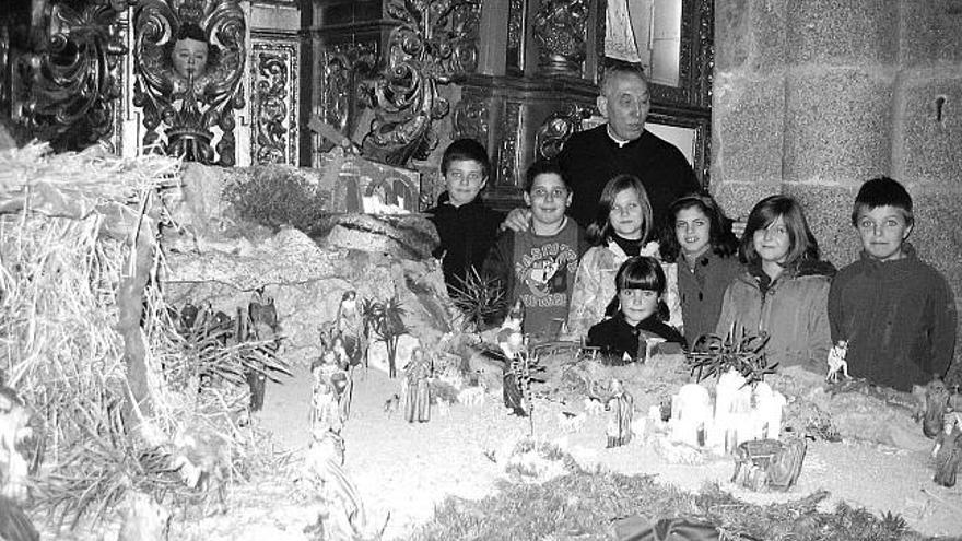 El canónigo Ricardo García, con monaguillos y niños de la parroquia, ante el gran belén.