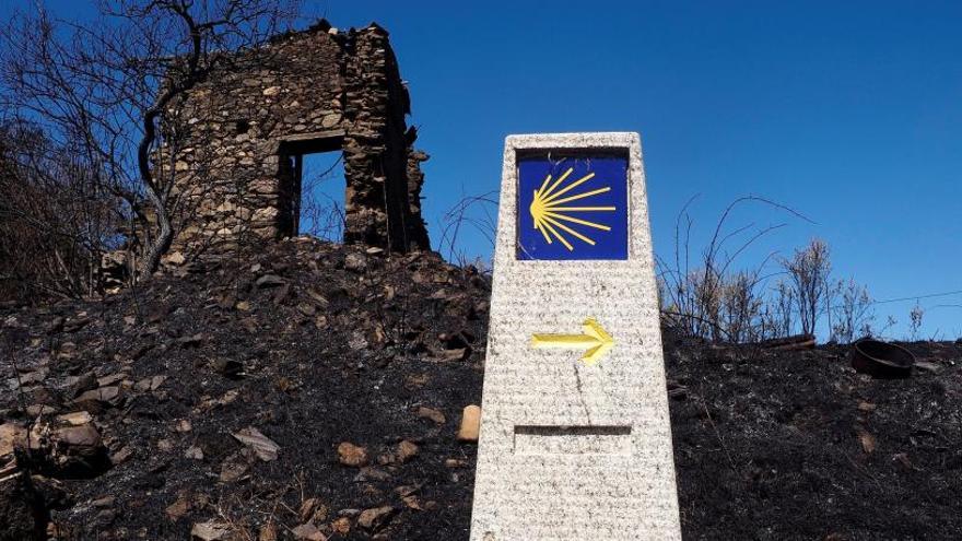 Hito del Camino de Santiago, junto a una vivienda calcinada en A Vide, una de las aldeas desalojadas en el incendio de Monforte que calcinó 430 hectáreas.