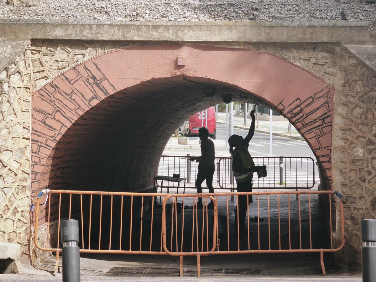 Dos artistas trabajan en pintar el otro mural bajo la N-340.