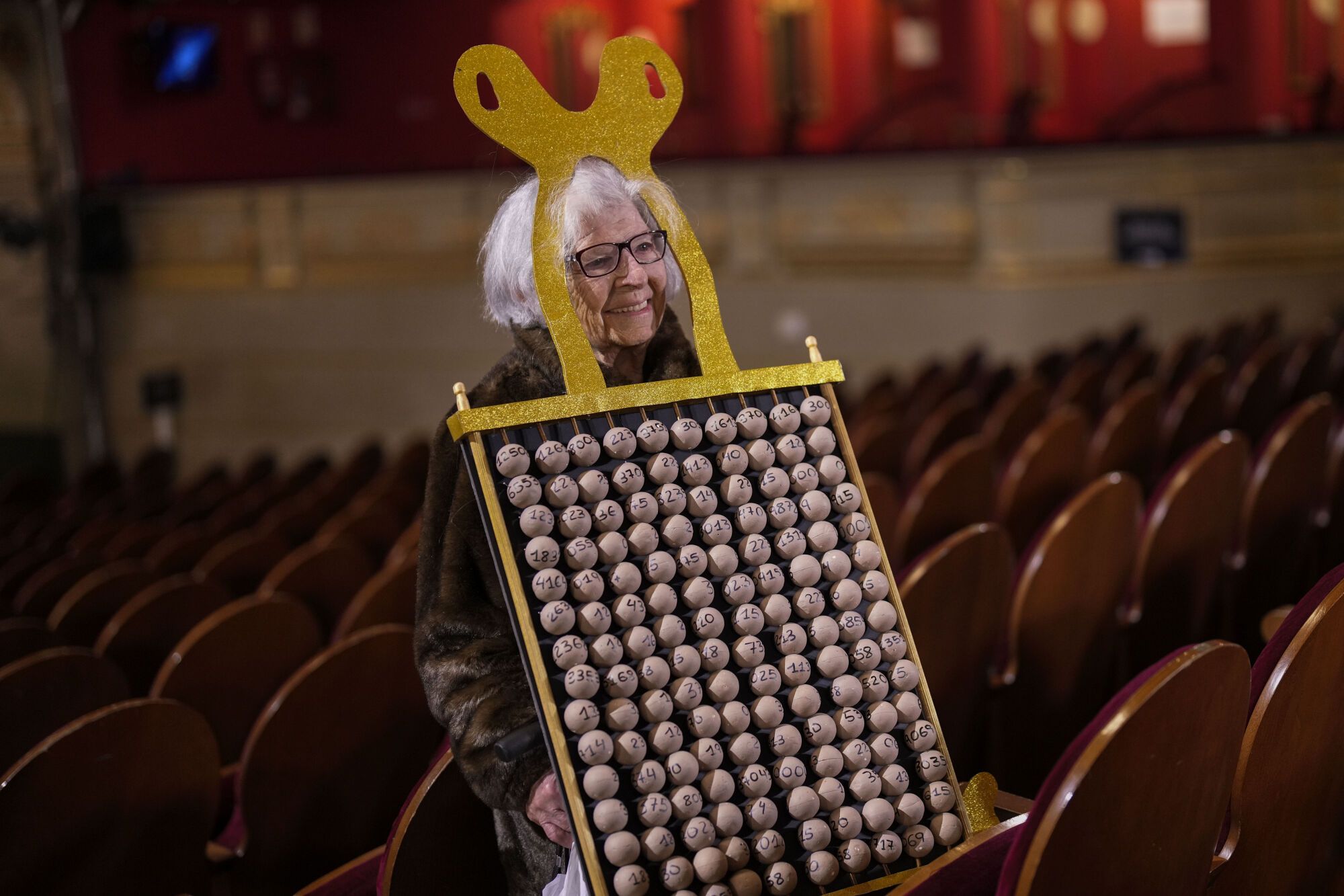 A spectator waits for the start of the annual Christmas lottery draw, known as El Gordo, or The Fat One, at Madrid's Teatro Real, Spain, on Sunday, Dec. 22, 2024. (AP Photo/Bernat Armangue)