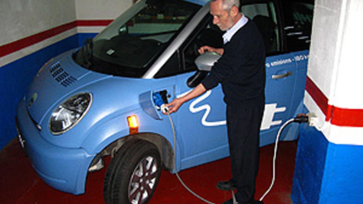 Un hombre carga la batería de un coche eléctrico