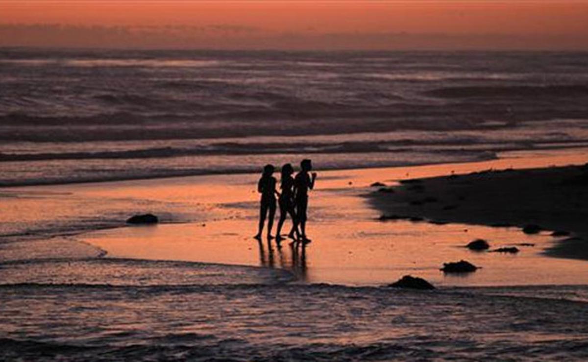 Diversos nens juguen durant la posta de sol a la platja de Cardiff, Califòrnia.