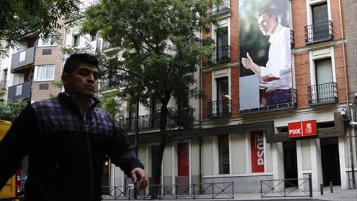 La fachada 8 Un peatón pasa frente a la sede principal del PSOE, con la gran foto del candidato a la Moncloa, ayer.