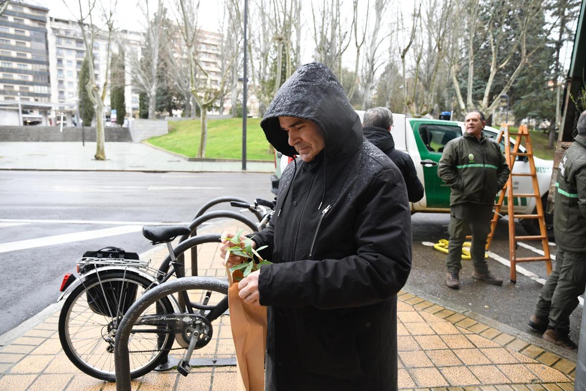 Un hombre, con la capucha puesta para protegerse de la lluvia y el plantón en su mano.