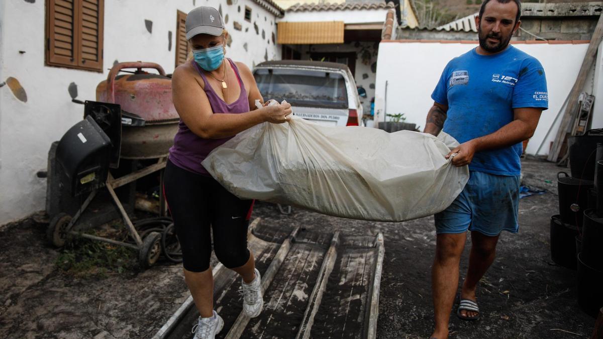 Un hombre y una mujer sacan sus pertenencias de su casa por la actividad del volcán de ‘Cumbre Vieja’