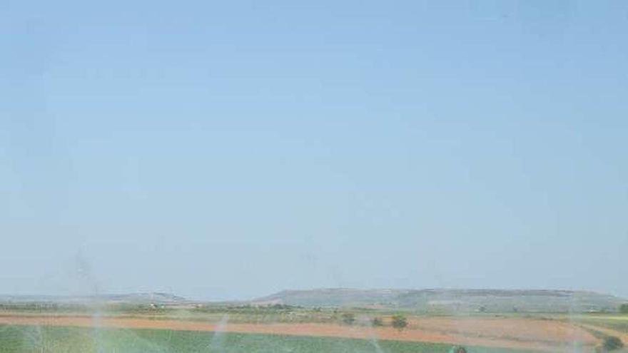 Un agricultor de la zona supervisa el riego de una parcela cultivada.