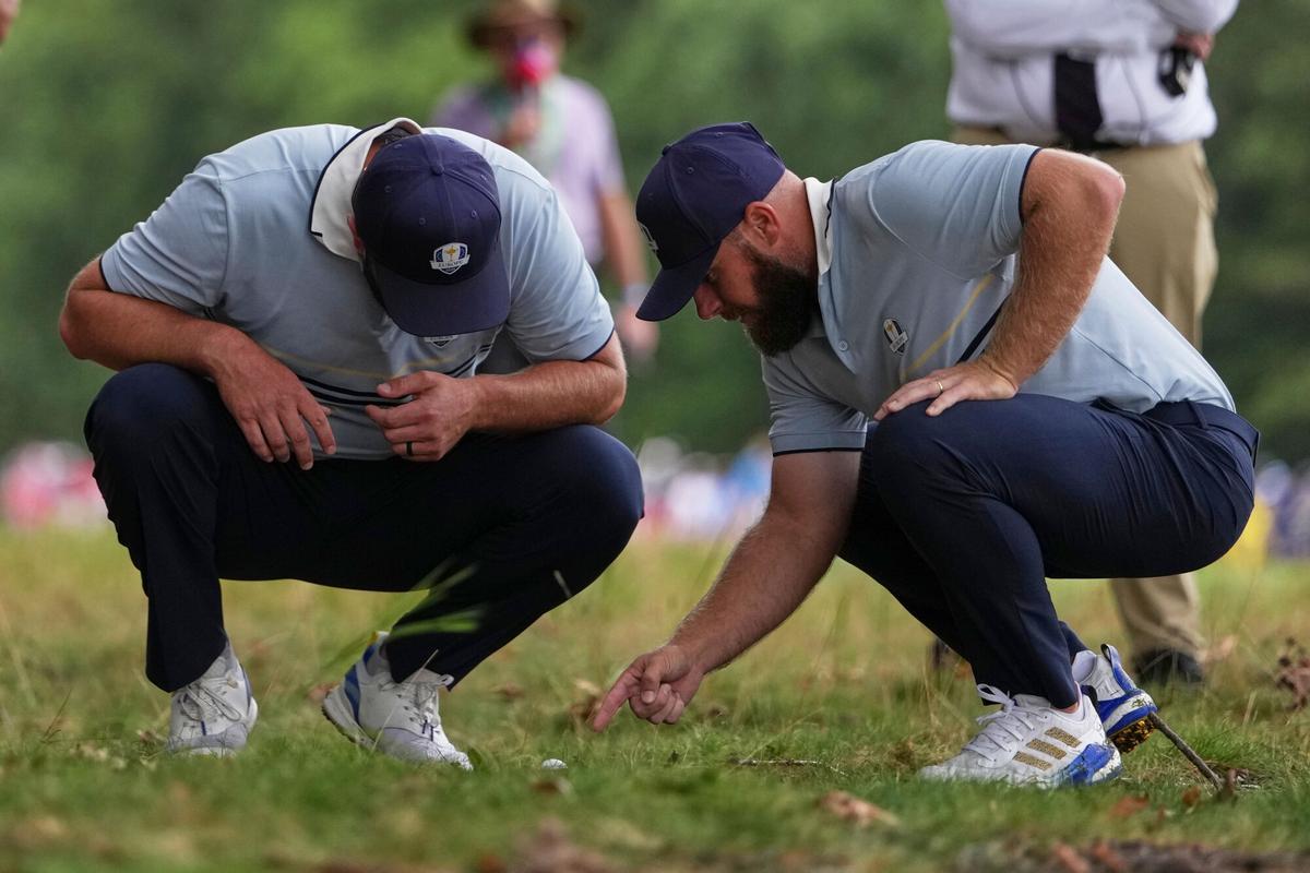 Tyrrell Hatton y Jon Rahm estudian una bola junto a una rama