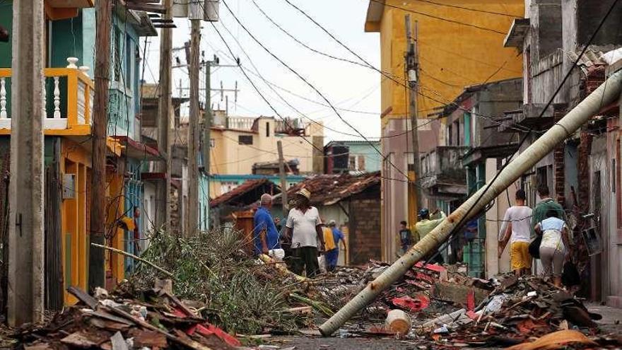 Residentes de la ciudad cubana de Baracoa caminan entre los destrozos que dejó &quot;Matthew&quot;. // Efe