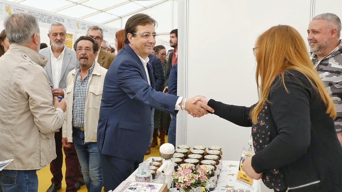 El presidente de la Junta de Extremadura, Guillermo Fernández Vara, visita un puesto de miel en una feria.