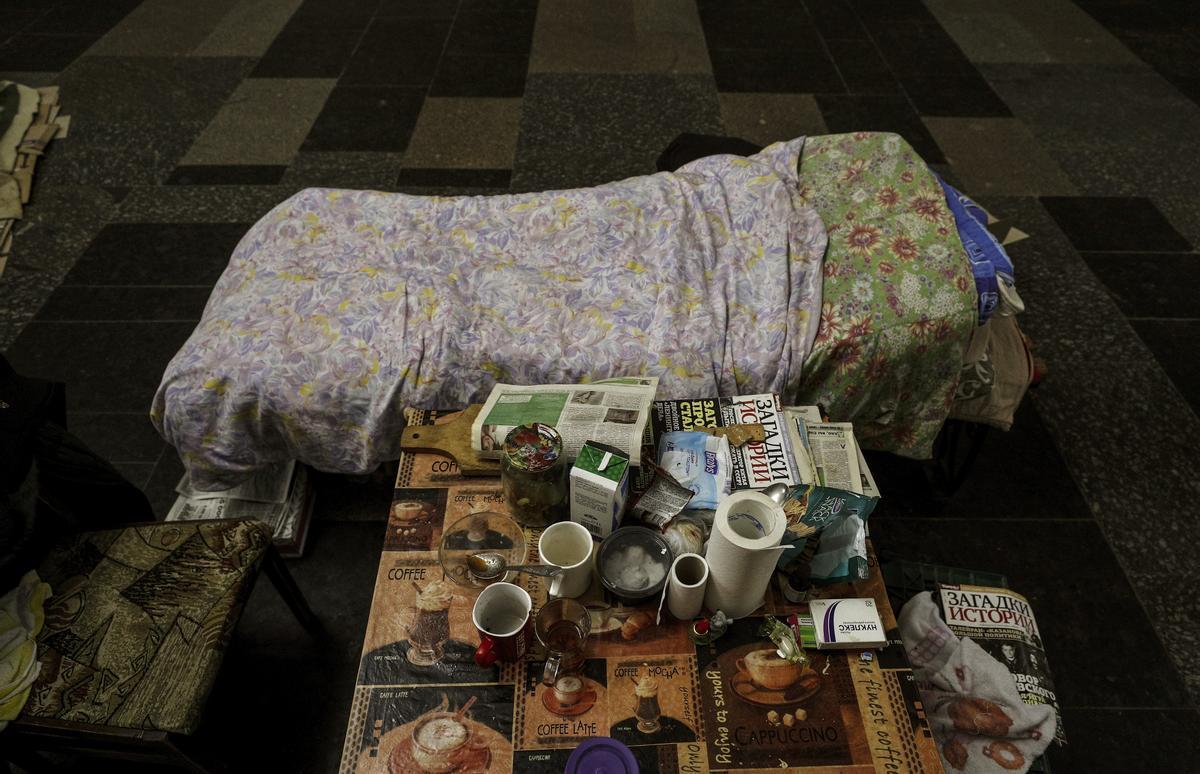 Una cama junto a una mesa con algunos artículos básicos, en el metro de Járkov.