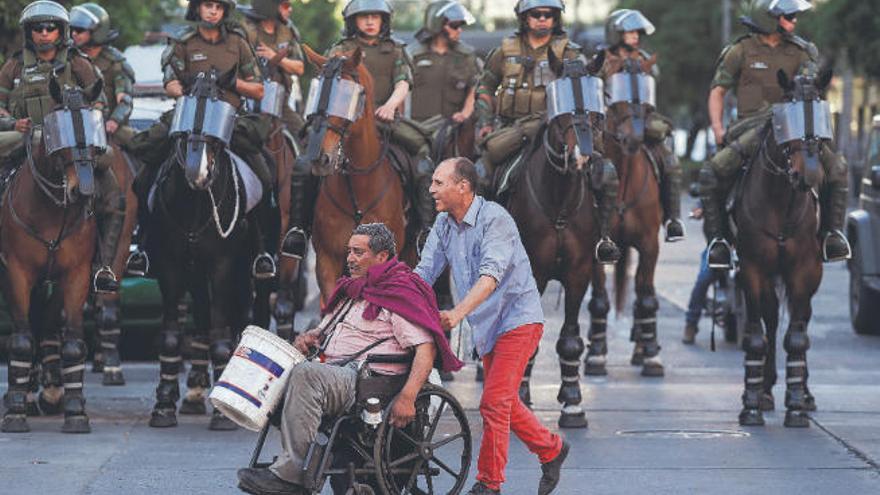Dos personas pasan frente a las fuerzas de seguridad durante las manifestaciones en Santiago de Chile.